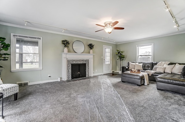 carpeted living room featuring ceiling fan, ornamental molding, rail lighting, and a tile fireplace