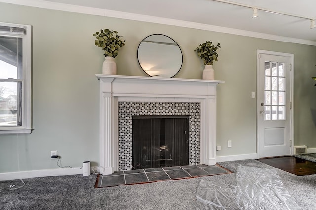 carpeted living room with rail lighting, ornamental molding, and a tile fireplace