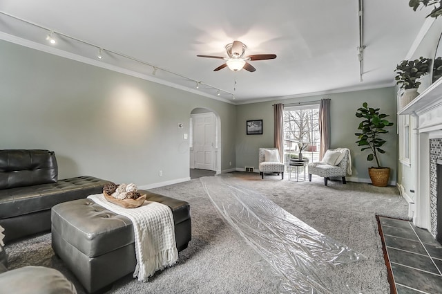 carpeted living room with ceiling fan, ornamental molding, and a fireplace