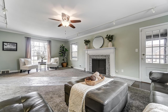 living room with ornamental molding, track lighting, ceiling fan, and a fireplace