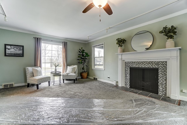 living area featuring dark carpet, a fireplace, ornamental molding, and rail lighting