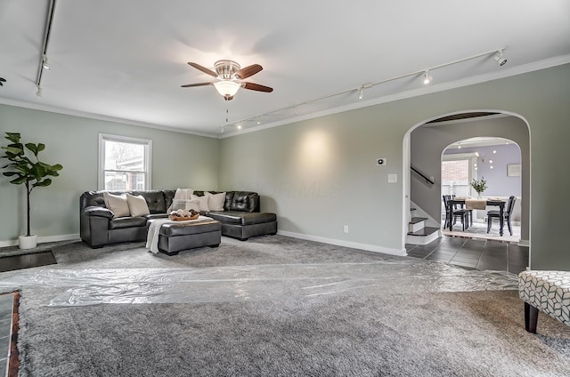 carpeted living room with ceiling fan, track lighting, and ornamental molding