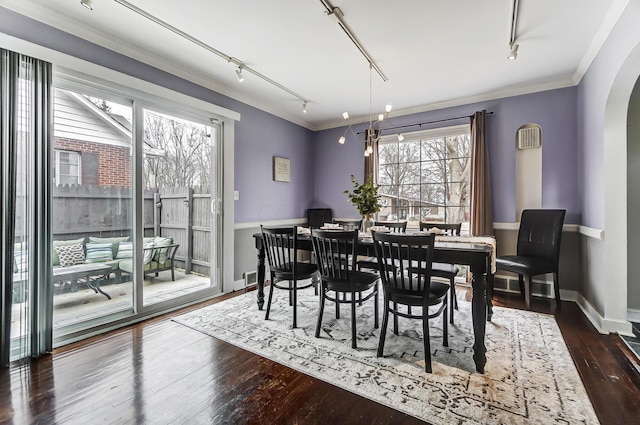 dining area with ornamental molding, dark hardwood / wood-style floors, and track lighting