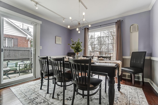 dining room with an inviting chandelier, ornamental molding, dark hardwood / wood-style floors, and rail lighting