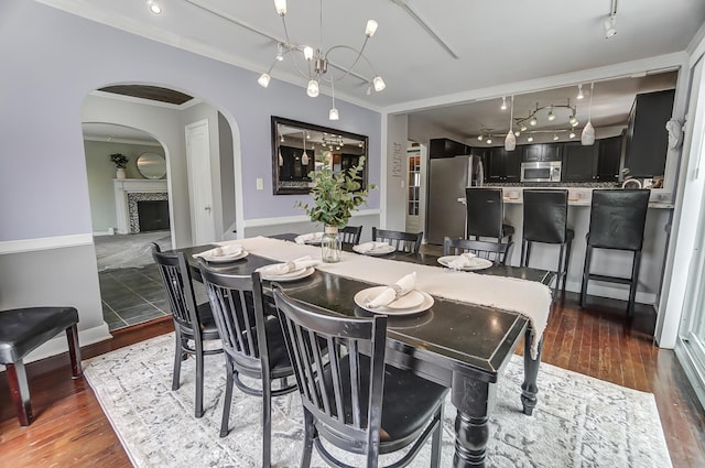 dining space featuring crown molding, track lighting, dark hardwood / wood-style flooring, and a notable chandelier