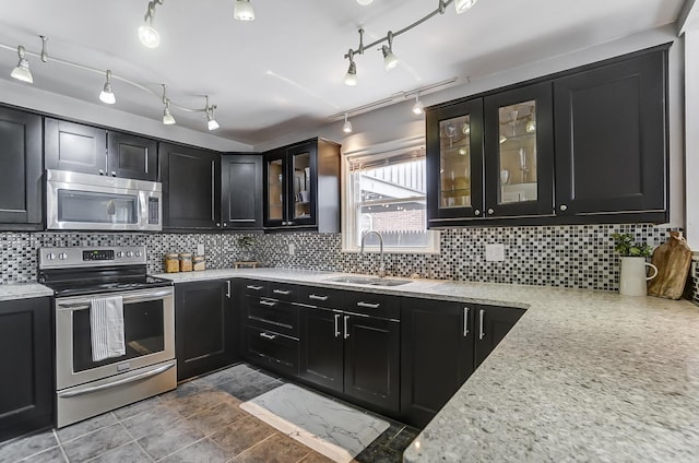 kitchen with stainless steel appliances, tasteful backsplash, light stone countertops, and sink