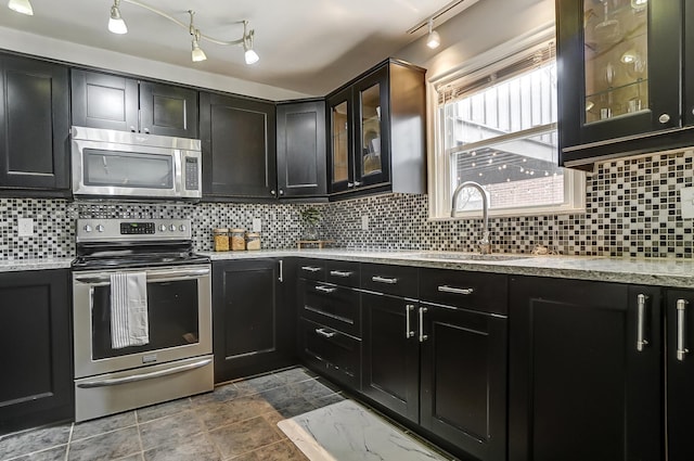 kitchen with light stone countertops, appliances with stainless steel finishes, sink, and backsplash