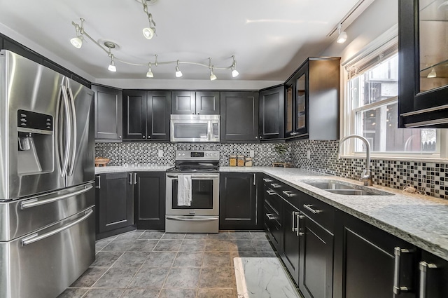 kitchen featuring stainless steel appliances, tasteful backsplash, light stone countertops, and sink