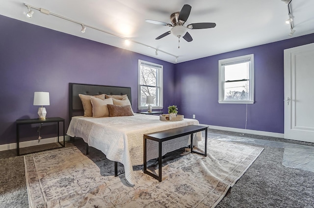 bedroom featuring ceiling fan, track lighting, and multiple windows