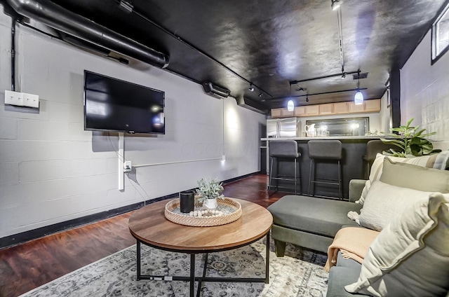 living room with dark hardwood / wood-style floors, track lighting, and bar area