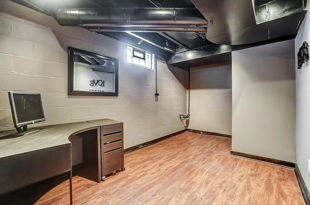 basement featuring built in desk and light hardwood / wood-style floors