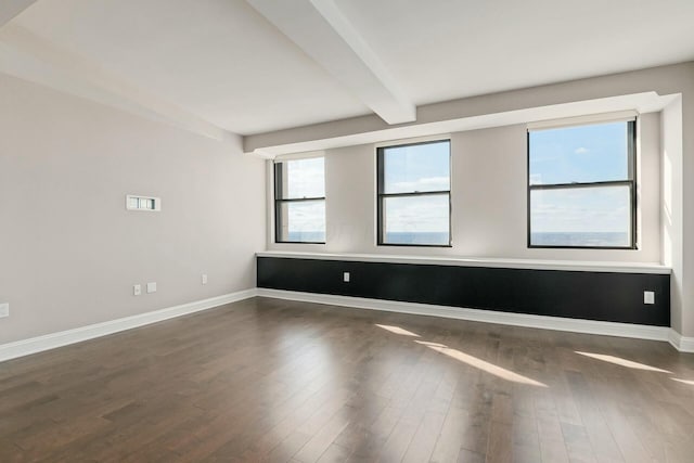 unfurnished room featuring dark wood-type flooring and beam ceiling