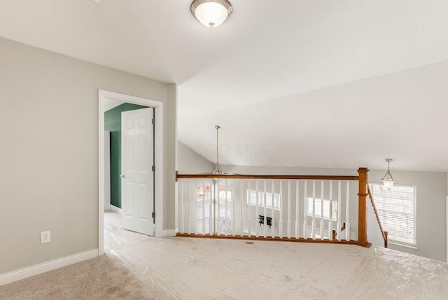 spare room featuring carpet, lofted ceiling, and baseboards