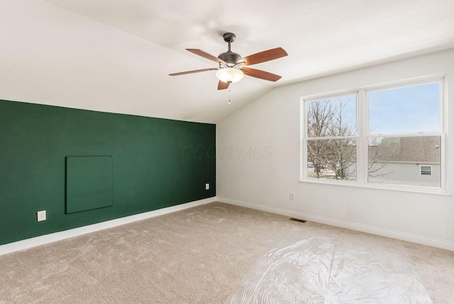 empty room with light carpet, visible vents, baseboards, a ceiling fan, and vaulted ceiling