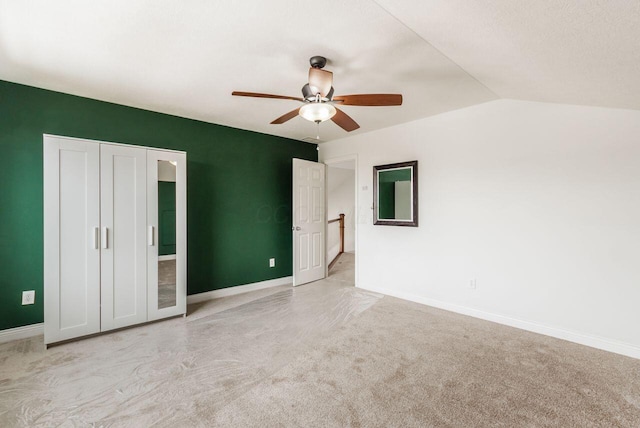 unfurnished bedroom featuring lofted ceiling, ceiling fan, light carpet, and baseboards