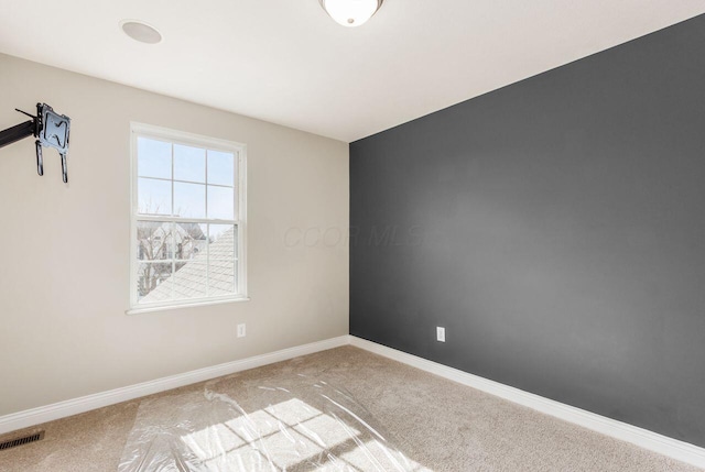 empty room featuring visible vents, light carpet, and baseboards