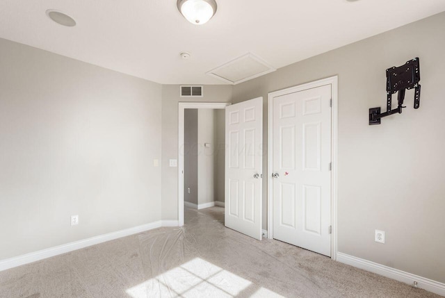 unfurnished bedroom with baseboards, light colored carpet, visible vents, and attic access