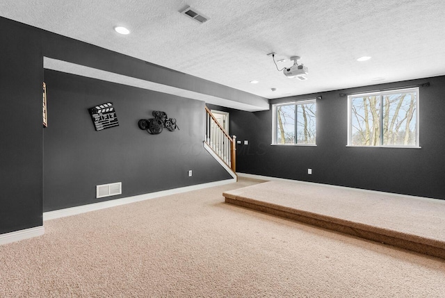 below grade area featuring carpet, visible vents, baseboards, and stairs