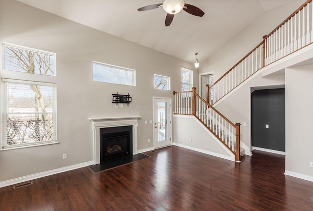 unfurnished living room featuring dark wood finished floors, visible vents, stairway, high vaulted ceiling, and baseboards