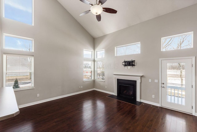 unfurnished living room with a fireplace with flush hearth, dark wood-style flooring, high vaulted ceiling, and baseboards