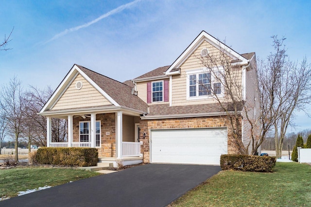 view of front facade with covered porch, a garage, stone siding, driveway, and a front lawn