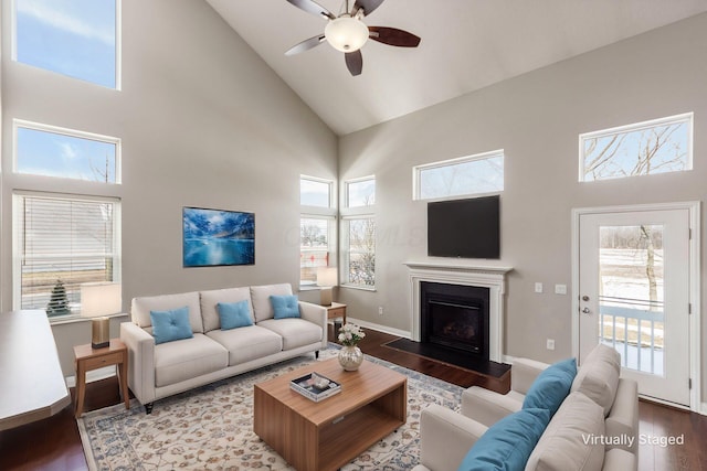 living room with high vaulted ceiling, a wealth of natural light, a fireplace, and wood finished floors