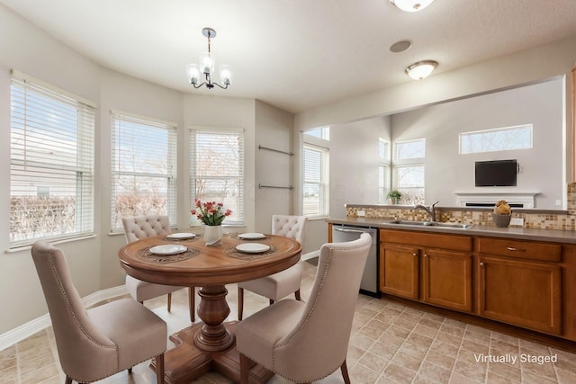 kitchen with brown cabinets, light countertops, stainless steel dishwasher, pendant lighting, and a sink