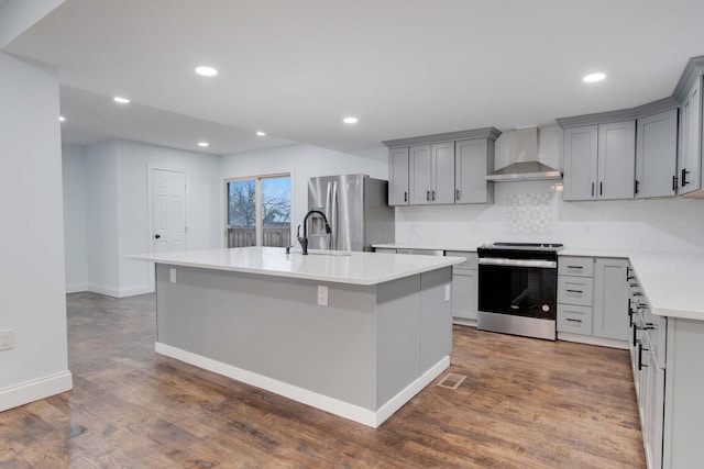 4874 Ridge St, Columbus, OH 43207 - kitchen featuring wall chimney range hood, gray cabinets, stainless steel appliances, and an island with sink