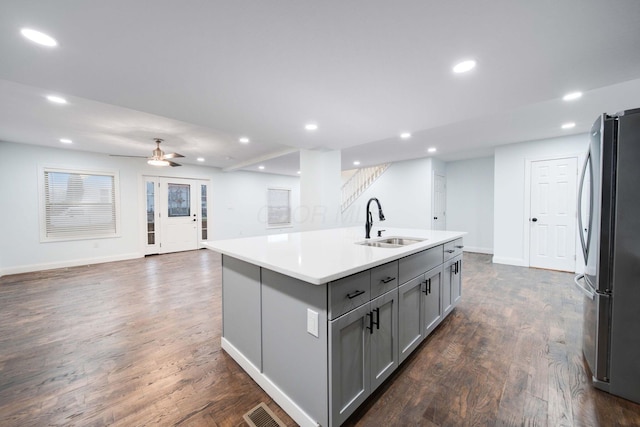 4874 Ridge St, Columbus, OH 43207 - kitchen with sink, stainless steel fridge, a kitchen island with sink, gray cabinetry, and dark hardwood / wood-style floors