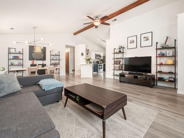 living room featuring ceiling fan with notable chandelier, lofted ceiling with beams, and light hardwood / wood-style flooring