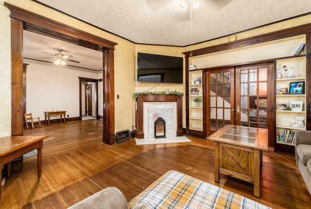 living room with ornamental molding, dark wood-type flooring, ceiling fan, and french doors