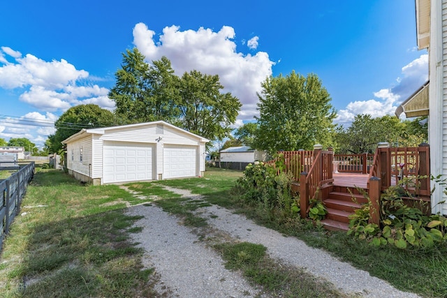 view of yard featuring a garage, a wooden deck, and an outbuilding