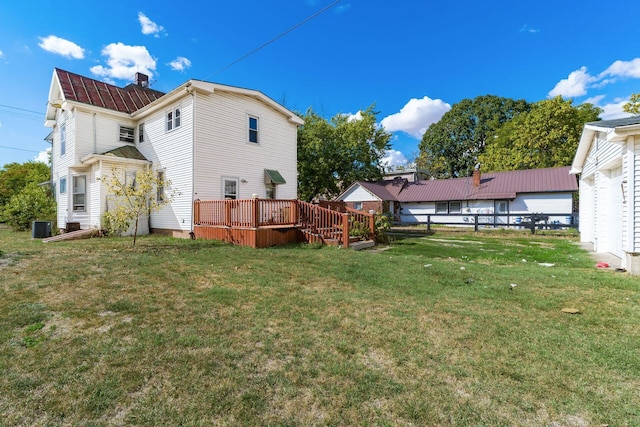 back of house featuring cooling unit, a wooden deck, and a yard