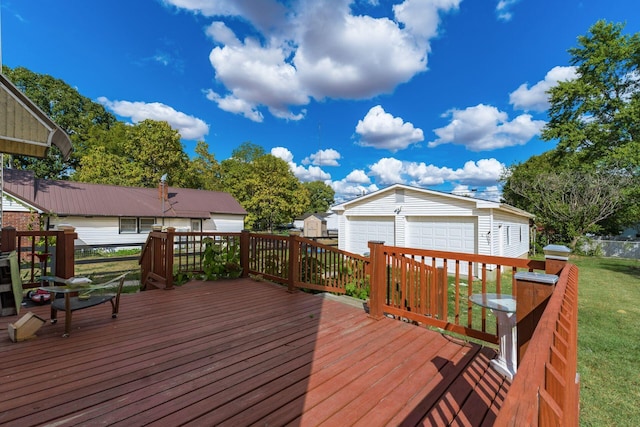 wooden deck with a garage, a yard, and an outbuilding