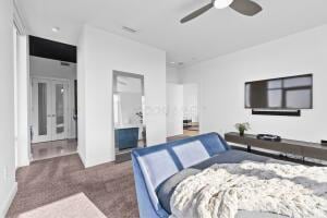 bedroom featuring dark colored carpet, ceiling fan, and ensuite bath