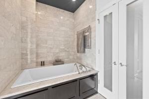 bathroom with a relaxing tiled tub and tile walls