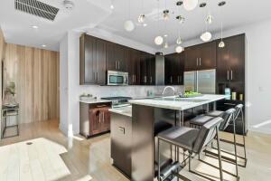 kitchen with a breakfast bar, decorative light fixtures, dark brown cabinets, a center island with sink, and appliances with stainless steel finishes