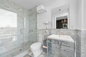 bathroom with tile walls, a shower with shower door, and toilet