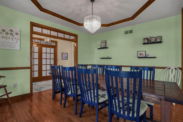 dining room with wood-type flooring, a raised ceiling, a chandelier, and french doors