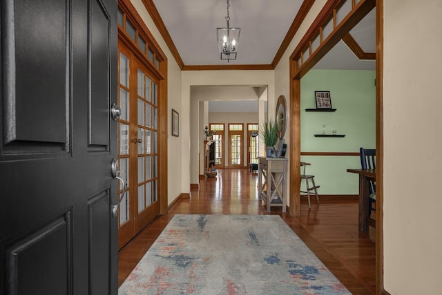 entrance foyer featuring french doors, dark hardwood / wood-style flooring, a chandelier, and crown molding