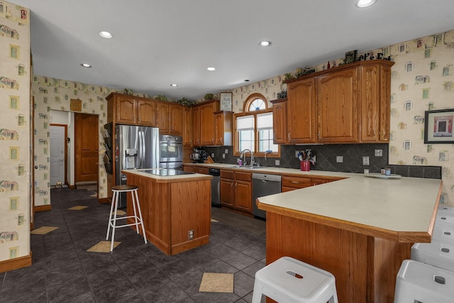 kitchen with sink, a kitchen breakfast bar, a center island, kitchen peninsula, and stainless steel appliances