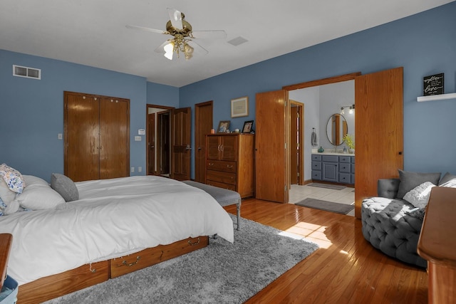 bedroom with sink, ensuite bathroom, ceiling fan, and light wood-type flooring