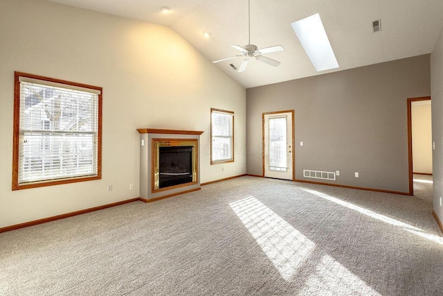 unfurnished living room with ceiling fan, light colored carpet, a skylight, and high vaulted ceiling