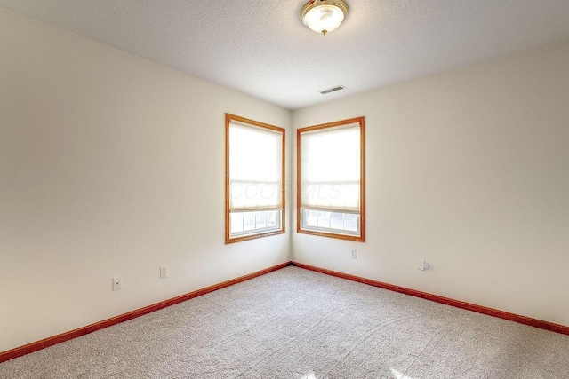 carpeted empty room with a textured ceiling