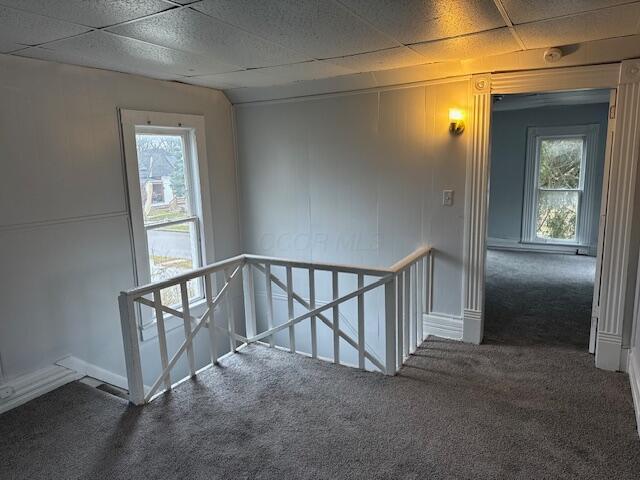 carpeted spare room featuring a paneled ceiling