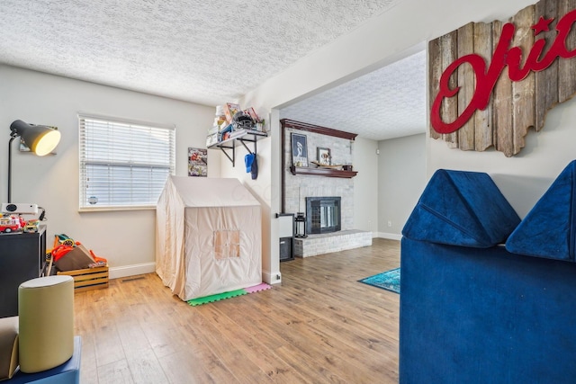 playroom featuring a fireplace, wood-type flooring, and a textured ceiling