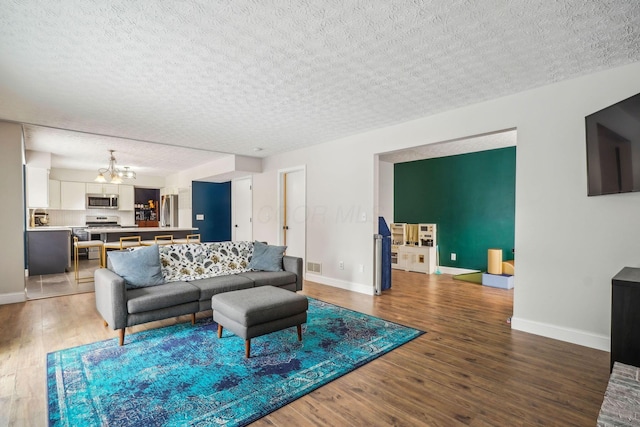 living room featuring wood-type flooring, a notable chandelier, and a textured ceiling