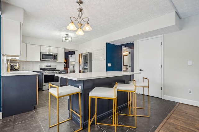 kitchen with white cabinetry, hanging light fixtures, stainless steel appliances, tasteful backsplash, and a kitchen island