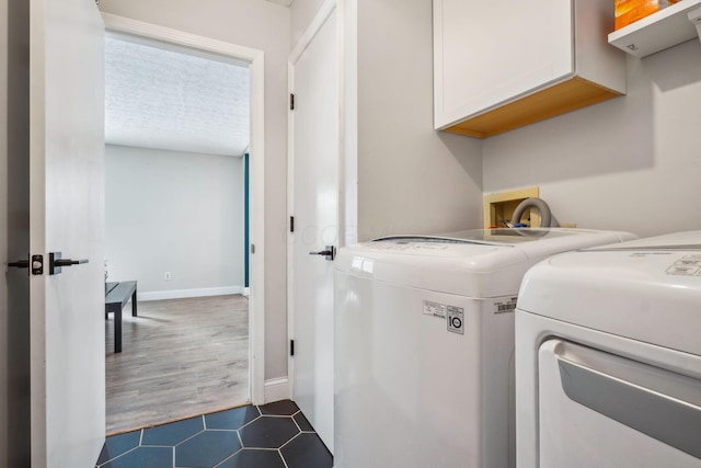 laundry room with cabinets, washer and dryer, and dark tile patterned floors