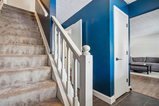 staircase with tile patterned flooring and a textured ceiling